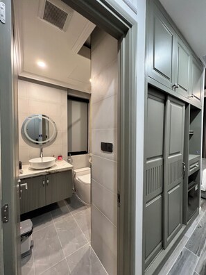 A modern bathroom with a round mirror, a white sink, and a toilet. - Palmera Villa Phu Quoc (Phu Quoc)