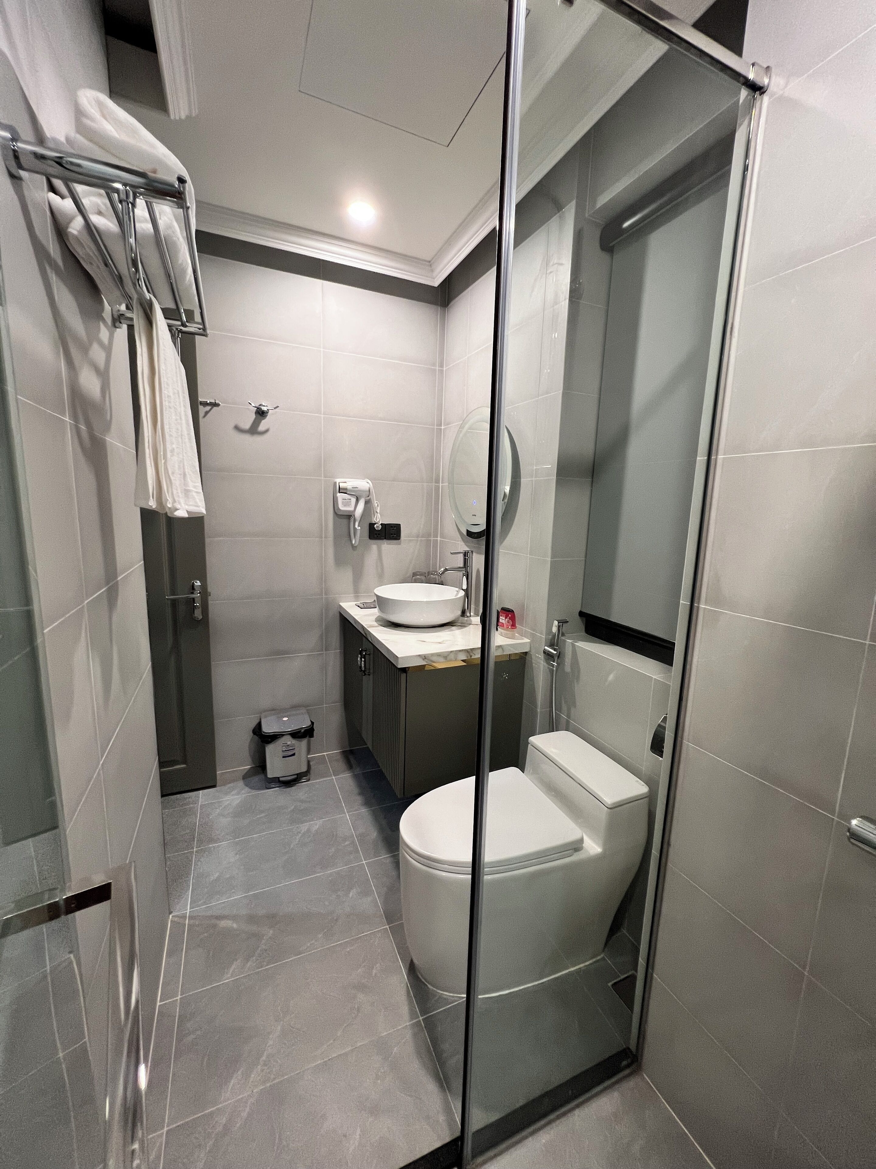 Une salle de bain moderne avec une douche à parois de verre, des toilettes, un lavabo et un porte-serviettes.