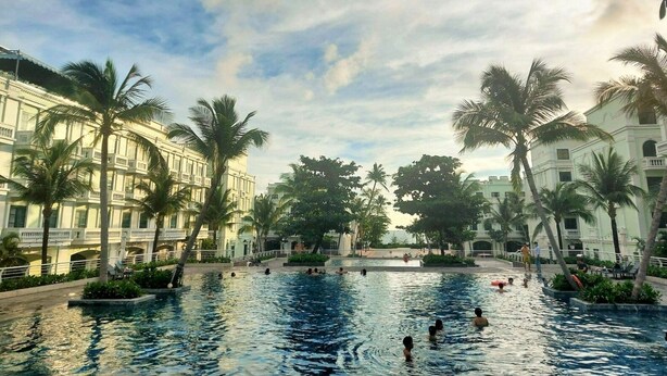 Ein Pool, umgeben von Palmen und einem Gebäude mit Balkonen.
