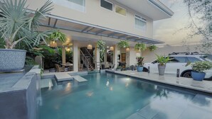 A modern house with a swimming pool, outdoor furniture, and potted plants.