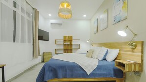 A bedroom with a wooden bed, bedside tables, a hanging light fixture, and artwork on the walls.