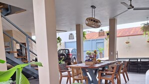 An outdoor dining area with a table and chairs, surrounded by large plants.
