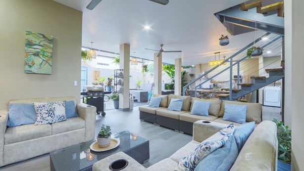 A spacious living area with a sofa set, a coffee table, and a staircase.