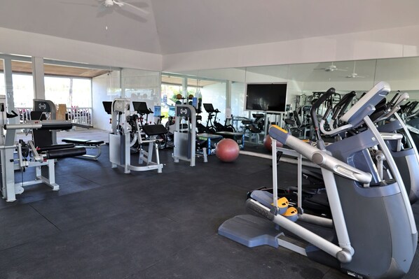 Une salle de sport moderne équipée de divers appareils d’exercice, notamment des tapis de course, des vélos d’appartement et des appareils de musculation.