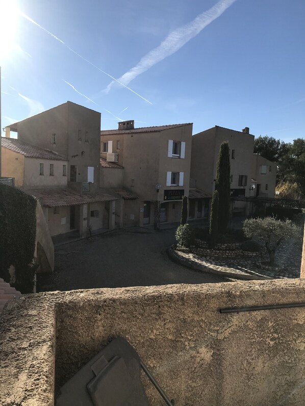 A courtyard with buildings, a sign for a pizza restaurant, and a clear sky.