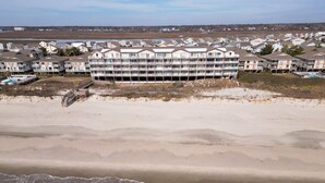 A beachfront hotel with multiple balconies, a sandy beach in the foreground, and a view of the ocean. - Oceanfront ! All linens included ! Stunning view ! 2BR/2BA.  WindJammer Condos (Ocean Isle Beach)