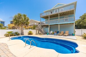 A two-story building with a pool, outdoor seating, and a wooden deck.