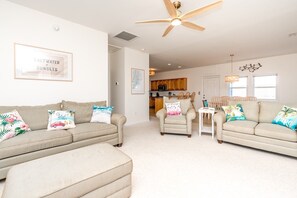 A living room with two beige sofas, a coffee table, and a ceiling fan.
