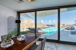 A modern interior with a large window overlooking a pool and a mountainous landscape.
