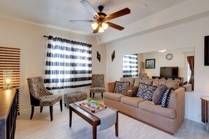 A living room with a sofa, two armchairs, a coffee table, and a ceiling fan.