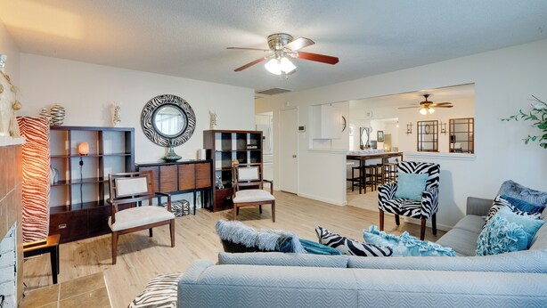 A spacious living room with a sofa, chairs, a bookshelf, and a dining area. - Near Airport & Dtwn: Breezy Fresno Home! (Fresno)