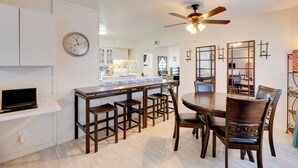 A modern kitchen with white cabinets, a wooden dining table, and a built-in bar area. - Near Airport & Dtwn: Breezy Fresno Home! (Fresno)
