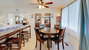 A dining area with a round table, wooden chairs, a ceiling fan, and a window with curtains. - Near Airport & Dtwn: Breezy Fresno Home! (Fresno)