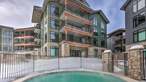 A multi-story building with balconies, a swimming pool, and stone pillars. - Downtown Winter Park Condo ~ 3 Mi to Skiing! (Winter Park)