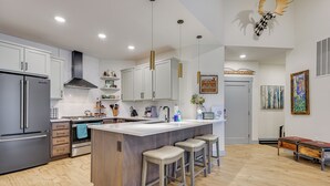 A modern kitchen with a central island, bar stools, and a refrigerator. - Downtown Winter Park Condo ~ 3 Mi to Skiing! (Winter Park)