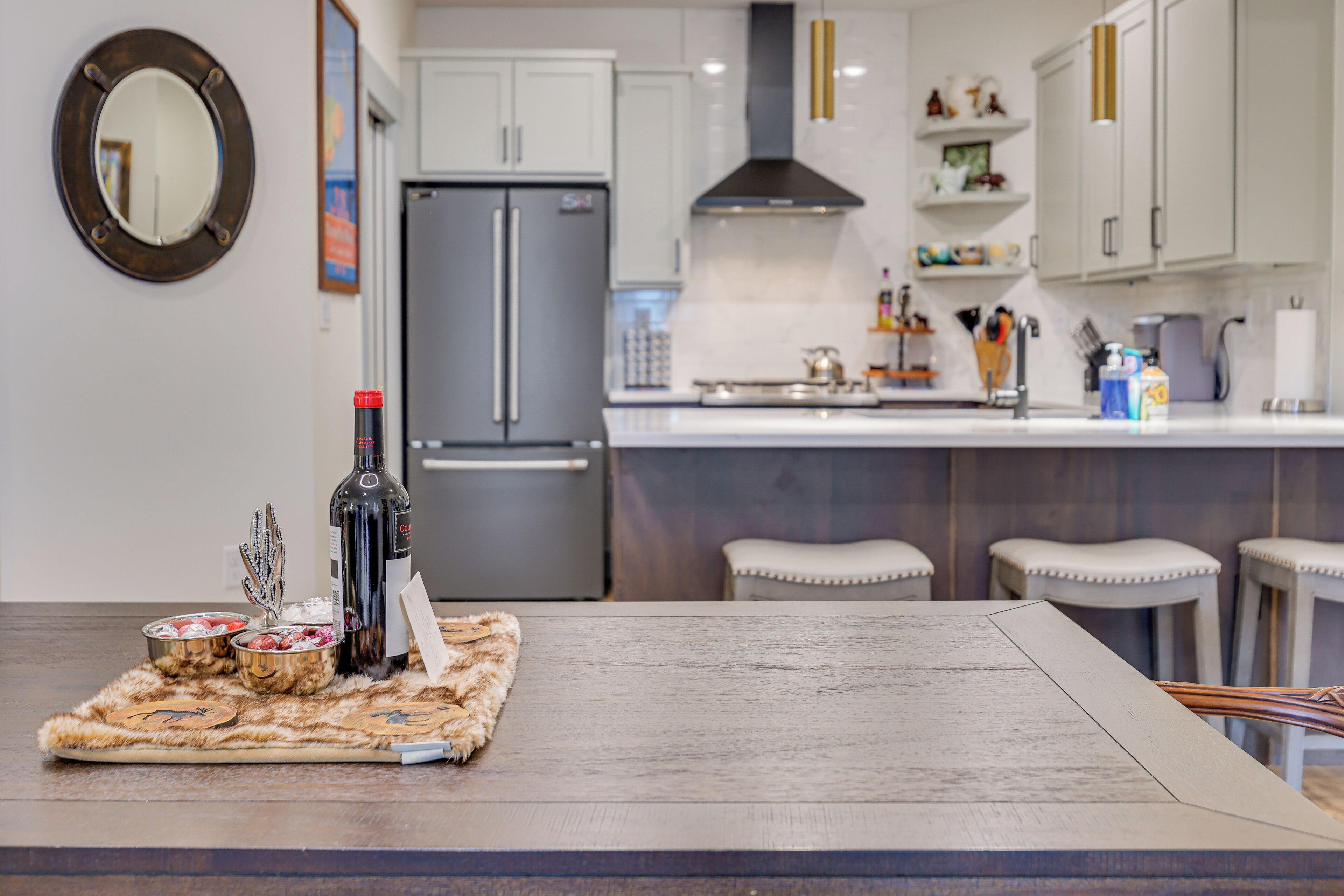 Une cuisine moderne dotée d’un îlot central, d’appareils électroménagers en acier inoxydable et de tabourets de bar.