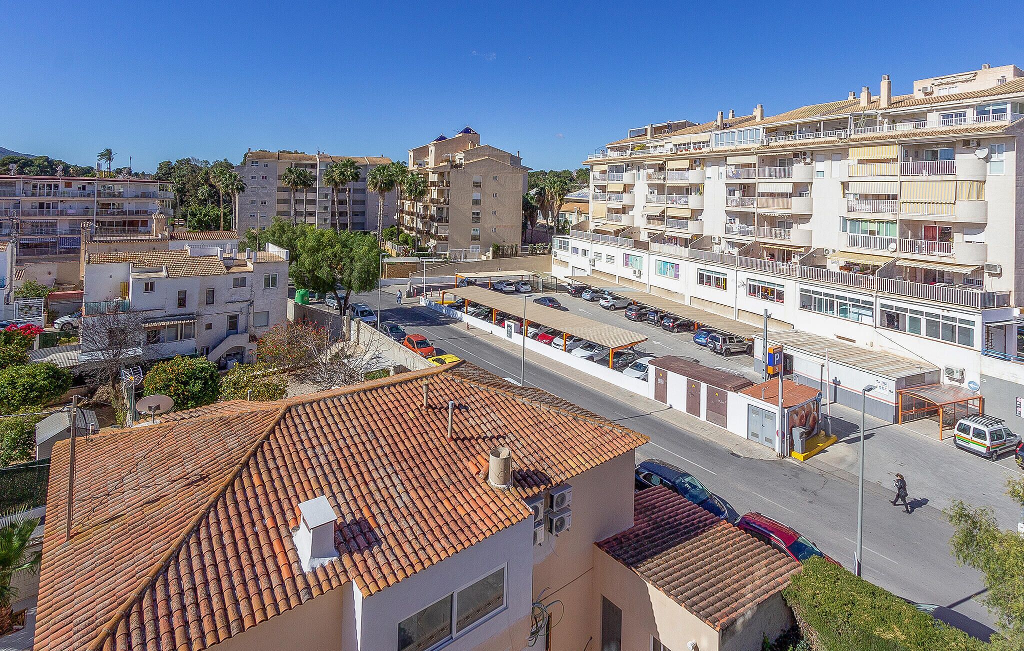 A coastal urban area with multi-story buildings, a parking lot, and a clear blue sky.