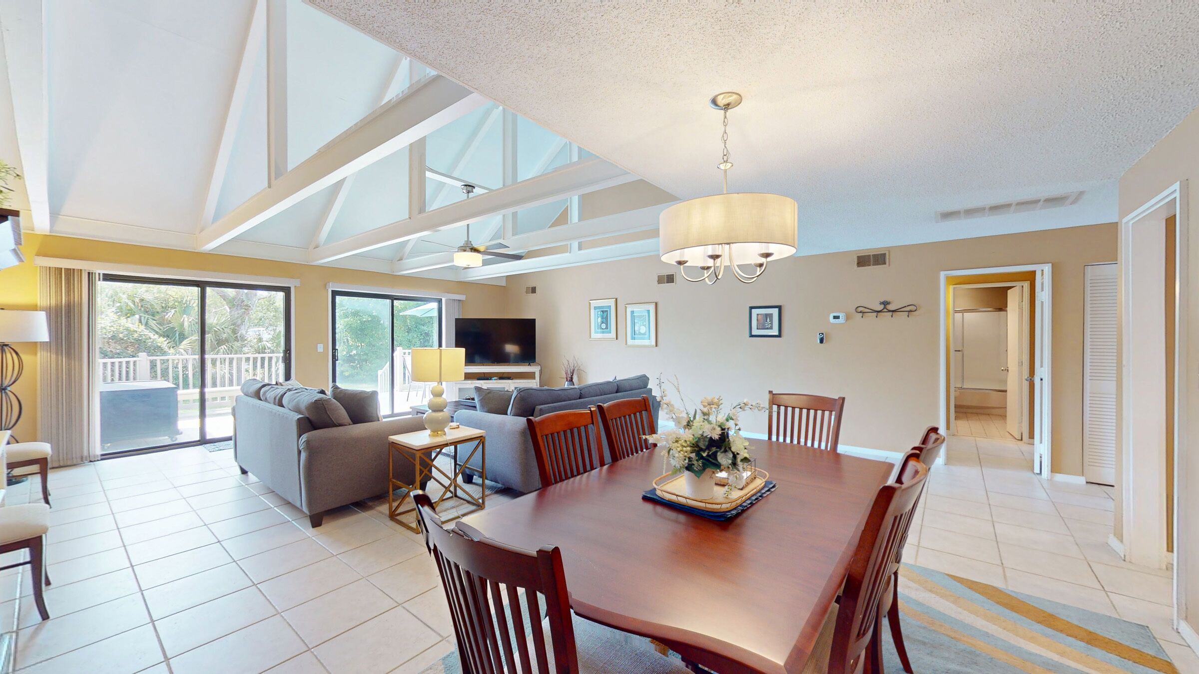 A spacious living area with a dining table, sofas, and a TV.
