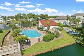 A residential area with a swimming pool, a dock, and a small boat. - Waterfront boat dock,very close to beach, pool, tennis courts, and sauna. (Panama City Beach)