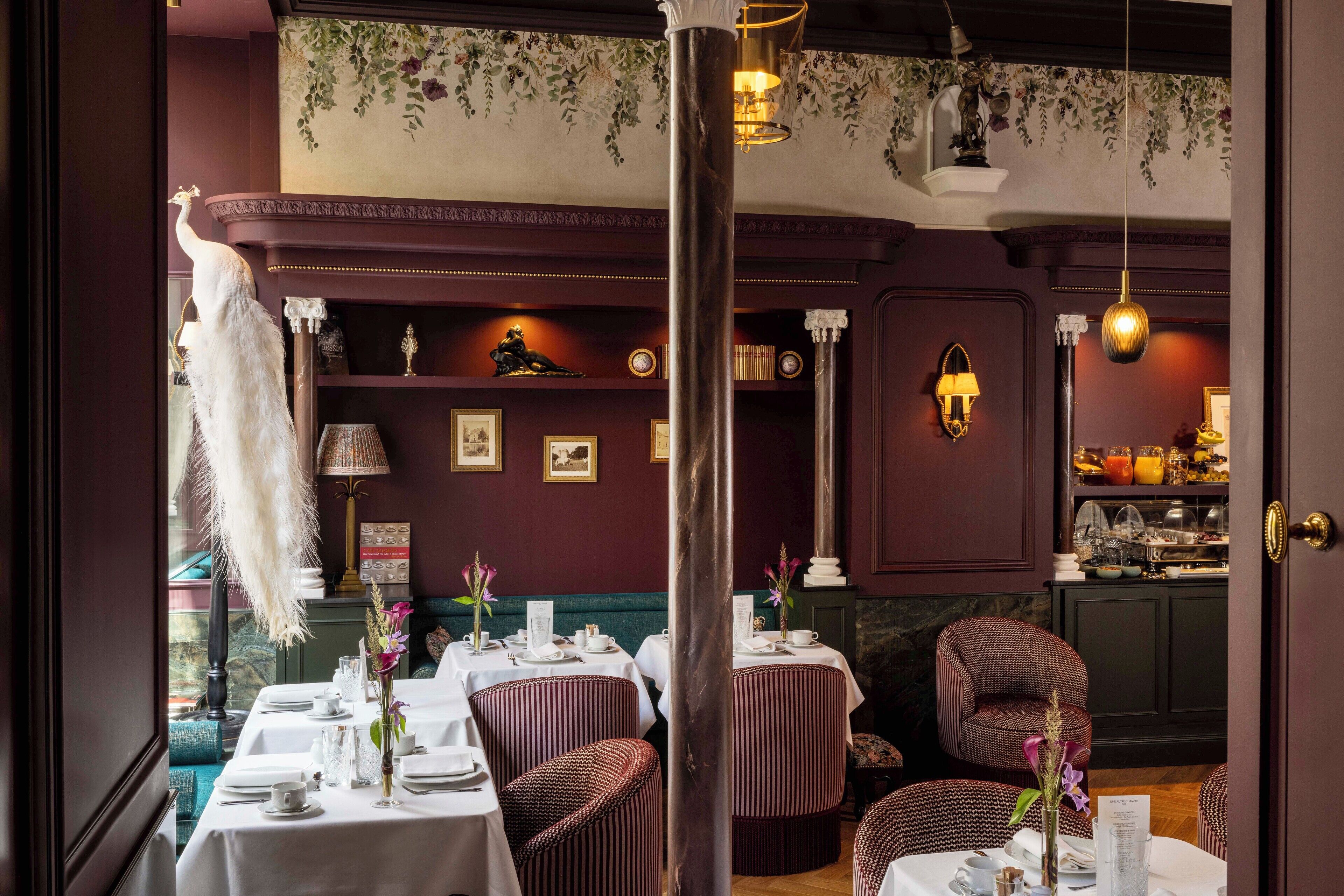 Un comedor con mesas dispuestas para el servicio, un pavo real decorativo y una zona de bar con diversos objetos.