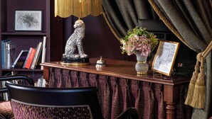 Taulell de recepció amb una estàtua de lleopard, una làmpada, un vas de flors i un expositor de menús.