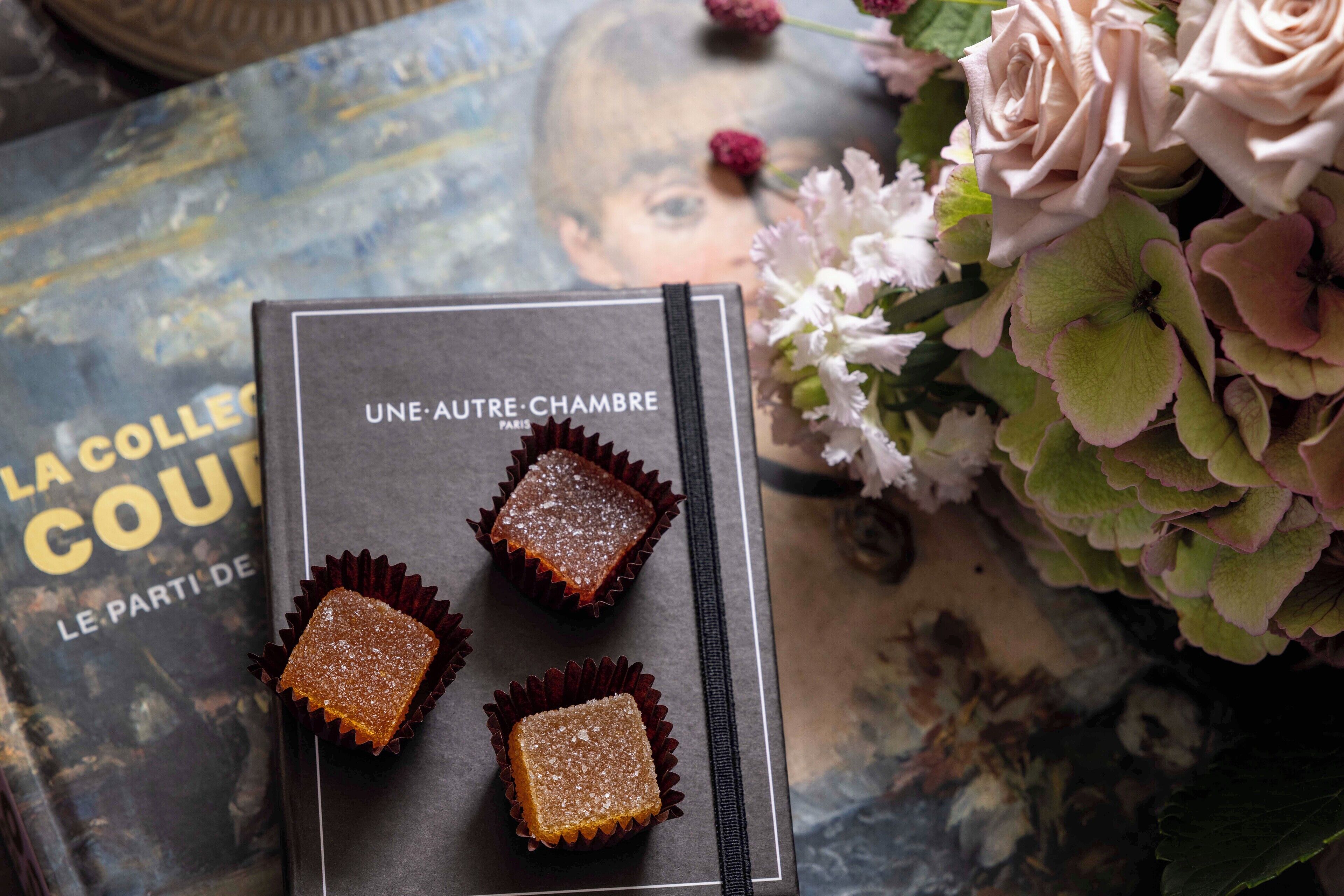 A book titled 'Une Autre Chambre' with three square chocolates on top.