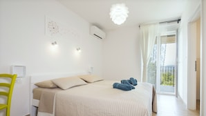Una camera da letto con un letto, una sedia, un condizionatore d'aria a muro e una finestra vista.
