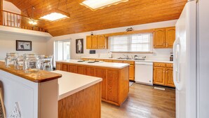 A spacious kitchen with wooden cabinets, a central island, and a white refrigerator. - 'deer Lake Lodge' on 700 Wooded Acres in Dayton! (Dayton)