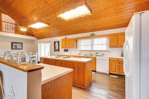 A spacious kitchen with wooden cabinets, a central island, and a white refrigerator. - 'deer Lake Lodge' on 700 Wooded Acres in Dayton! (Dayton)