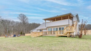 A two-story house with a wooden deck, a covered porch, and a large window overlooking a grassy yard. - 'deer Lake Lodge' on 700 Wooded Acres in Dayton! (Dayton)
