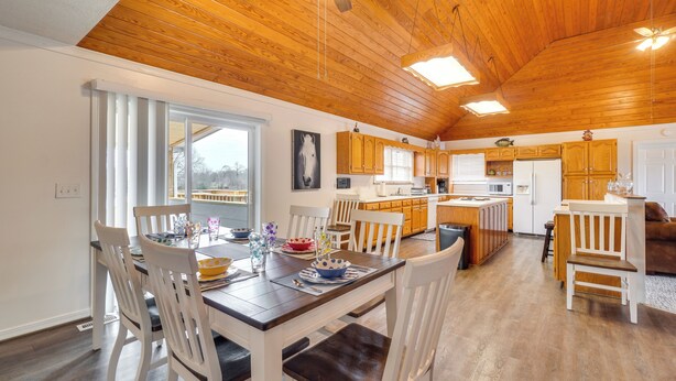 A spacious kitchen with wooden cabinets, a dining area with white chairs, and a ceiling fan. - 'deer Lake Lodge' on 700 Wooded Acres in Dayton! (Dayton)