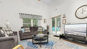 Un salon avec un canapé, une table basse, un téléviseur et une horloge au mur.