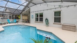 Une piscine intérieure dotée d’un toit en verre, entourée de chaises bleues, et un tuyau pour l’entretien de la piscine.