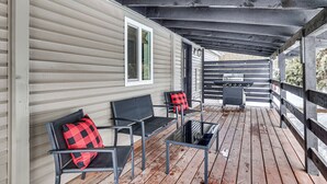 A covered porch with two black chairs and a table, a barbecue grill, and a window with a green frame. - Downtown Cascade Vacation Rental < 1 Mi to Lake! (Cascade)