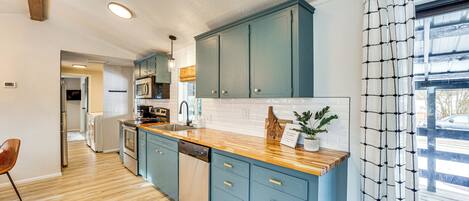 A modern kitchen with blue cabinets, wooden countertops, and a dishwasher.