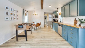 A modern kitchen with blue cabinets, a wooden dining table, and a foosball table. - Downtown Cascade Vacation Rental < 1 Mi to Lake! (Cascade)
