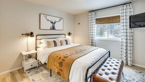 A bedroom with a bed, bedside tables, a bench, a window with curtains, and a wall-mounted TV. - Downtown Cascade Vacation Rental < 1 Mi to Lake! (Cascade)