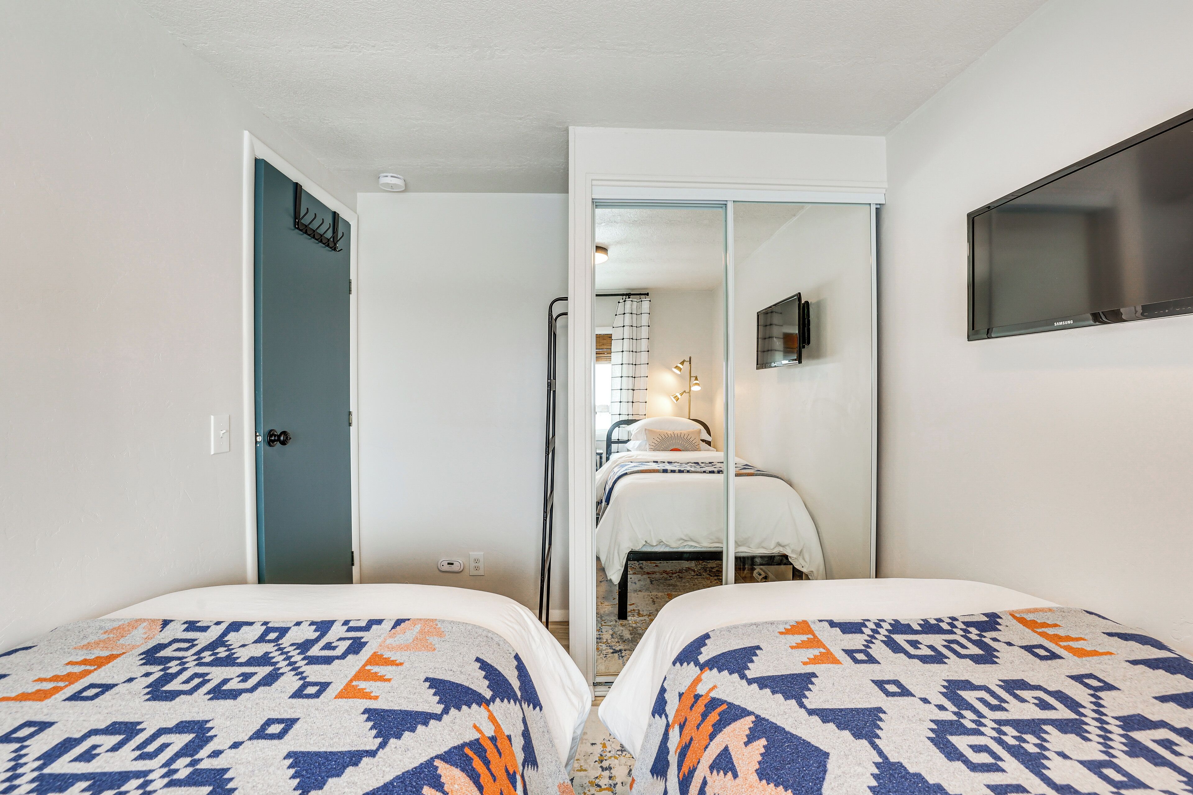 Un dormitorio con dos camas, un televisor y un baño que se ve a través de una puerta abierta.