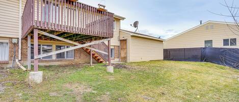 A two-story house with a wooden deck, a satellite dish, and a fenced yard.