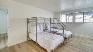 A bunk bed room with a wooden floor, white walls, and a window with a view of a building. - Salt Lake County Home Near 4 Major Ski Resorts! (Midvale)