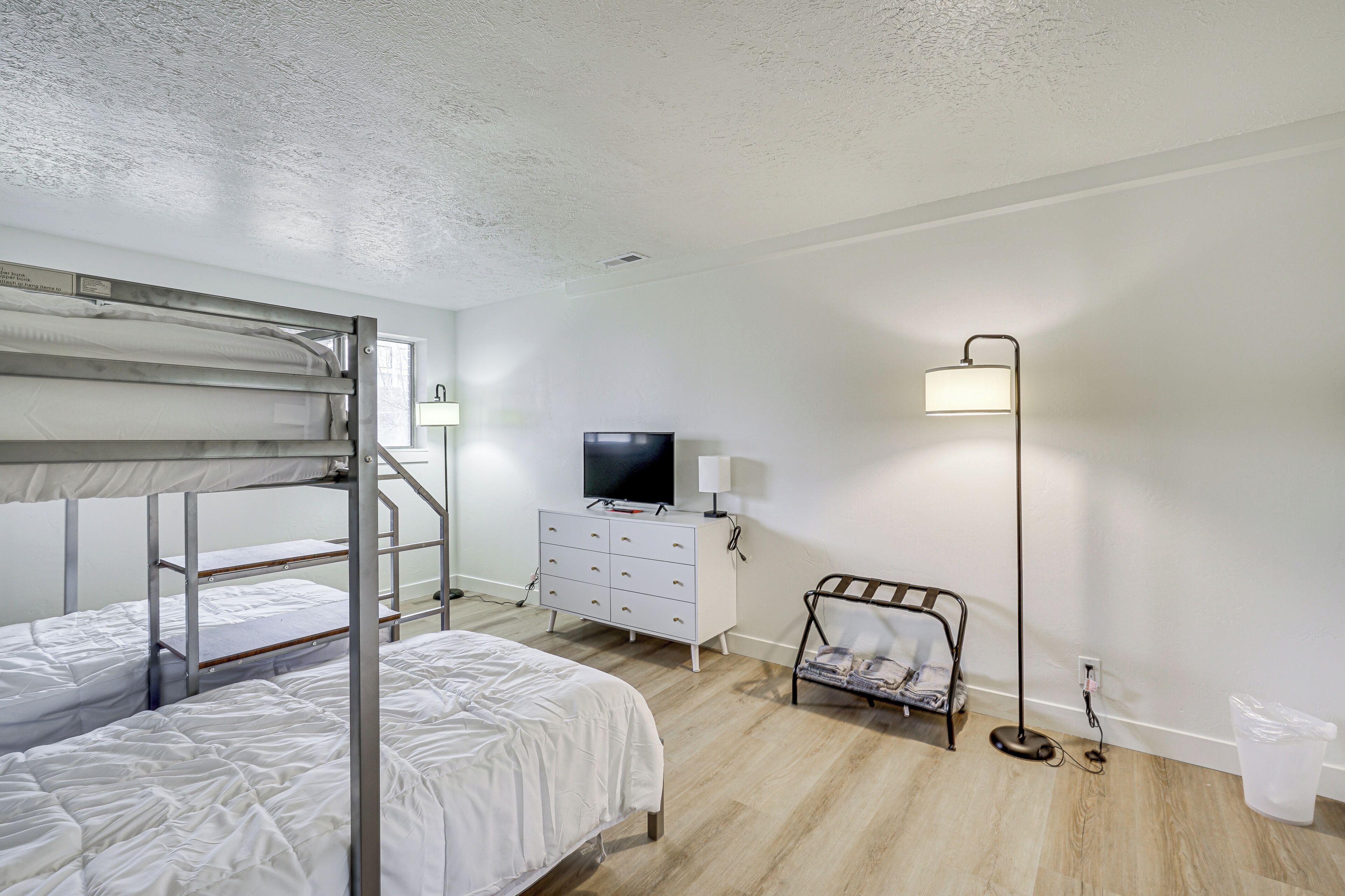 A bedroom with bunk beds, a TV, a dresser, and a floor lamp.