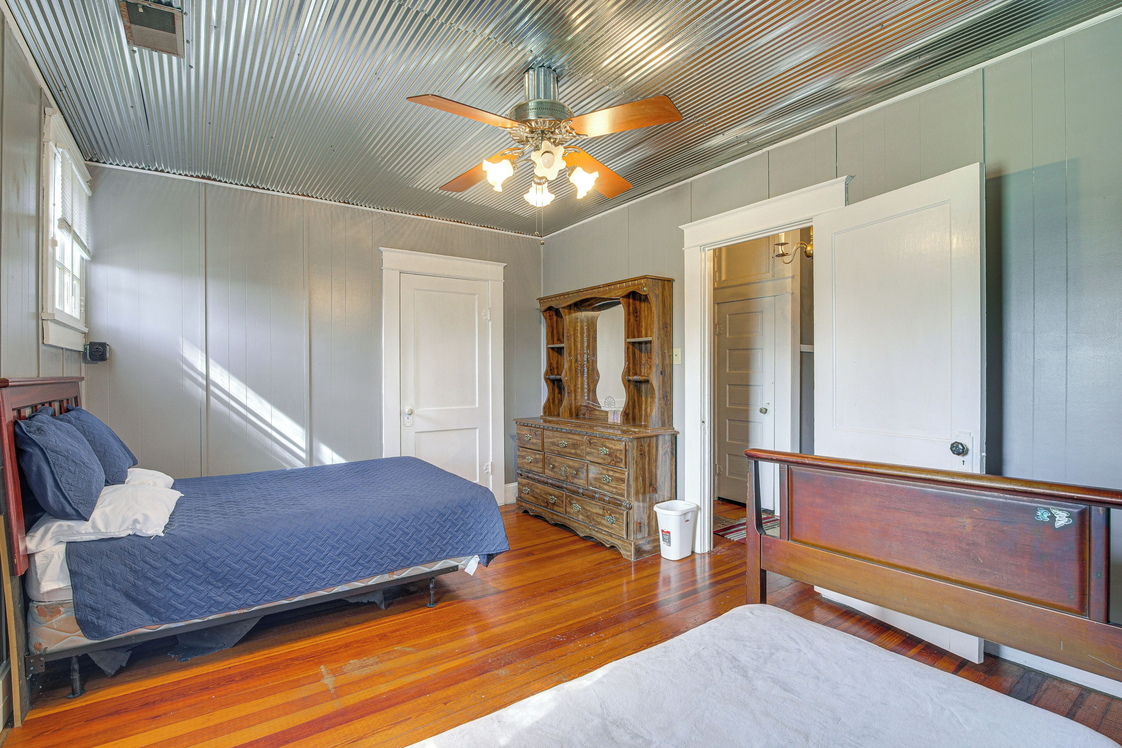A bedroom with a bed, dresser, mirror, and ceiling fan.