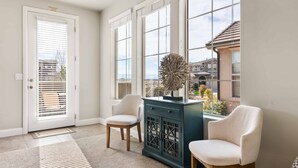 A room with a large window, a door with blinds, a cabinet, and two chairs. - Red Cliffs Getaway 3 Bedroom Townhouse (Washington)