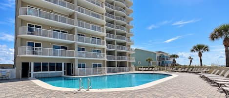 A multi-story hotel with a swimming pool and outdoor seating.