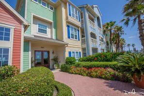 A multi-story hotel with colorful exterior walls, a brick pathway, and well-maintained landscaping.