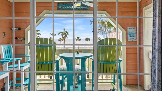 A room with a view of the beach, a ceiling fan, and a sign that reads "The Beach". - Ocean & Pool Views, W/D in Condo, 2 King Beds (Galveston)