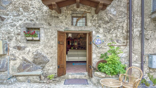A stone building with a wooden door, a small window, and a sign that reads "Valle Enchamps."