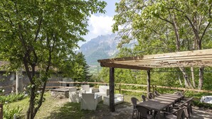 An outdoor seating area with a wooden pergola, wicker furniture, and a view of mountains.