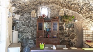 A rustic kitchen with stone walls, wooden cabinets, and a small window.