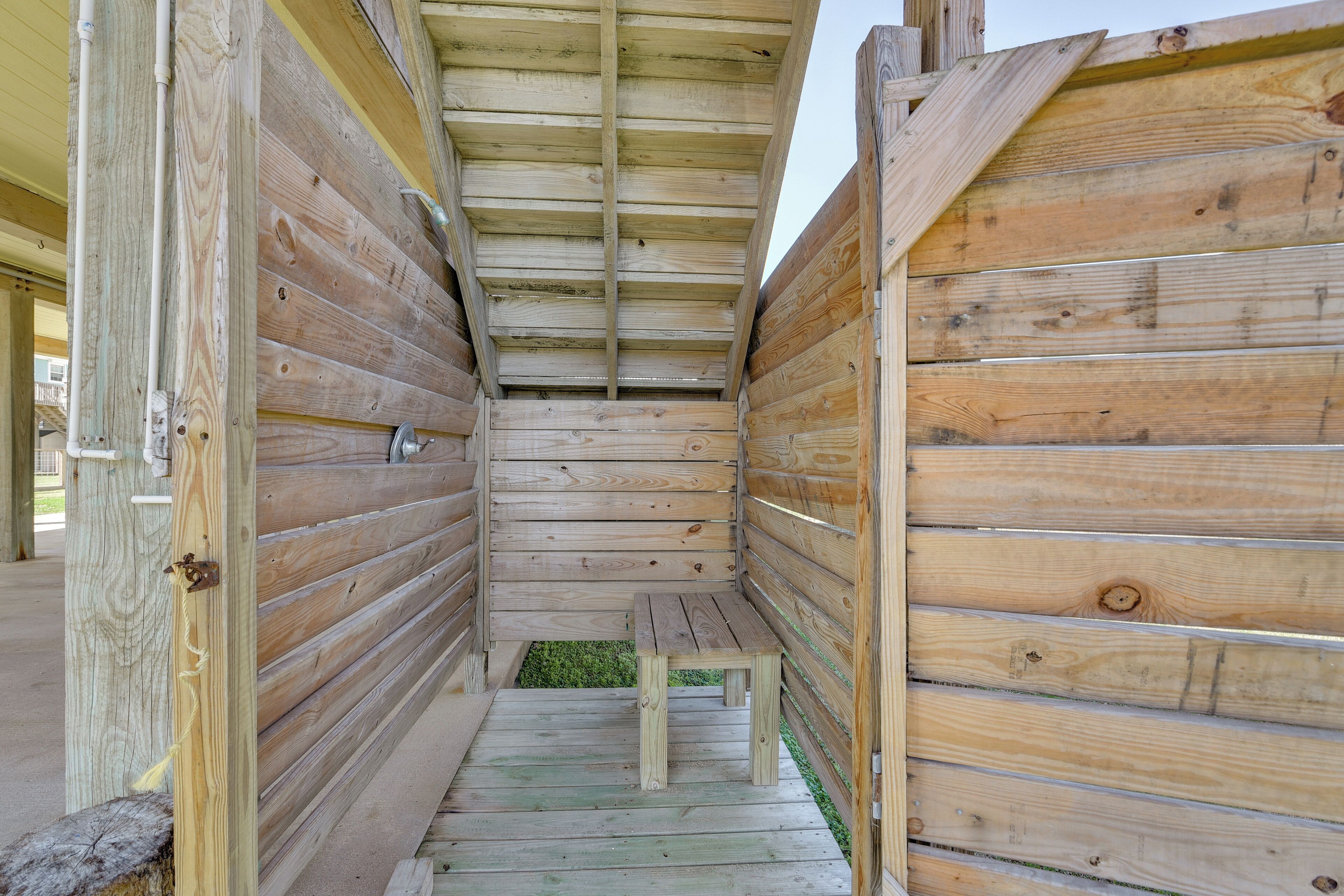 A wooden cabin with a bench in the center, a small window, and a door on the left.
